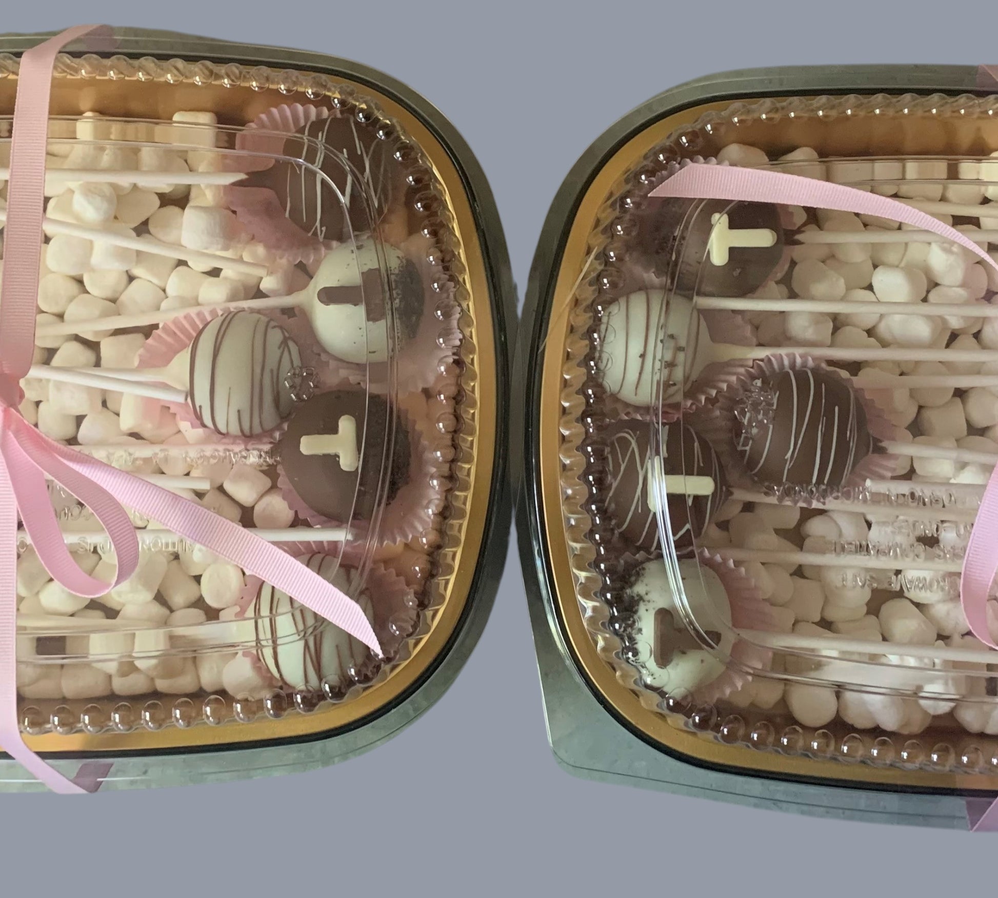 Sarah's Cakes dozen cake pops, assorted chocolate and white chocolate drizzle, presented in a clear container with pink ribbon and mini marshmallows.