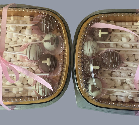 Sarah's Cakes dozen cake pops, assorted chocolate and white chocolate drizzle, presented in a clear container with pink ribbon and mini marshmallows.