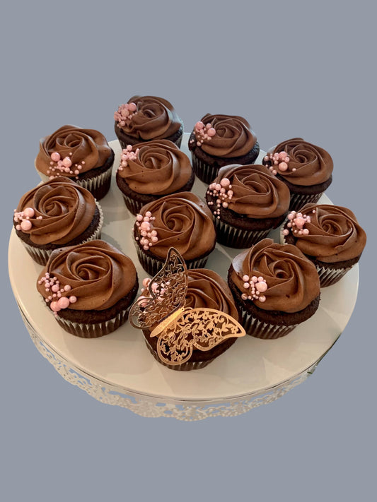 Sarah's Cakes chocolate cupcakes with chocolate frosting, topped with pink pearls and a gold butterfly decoration.
