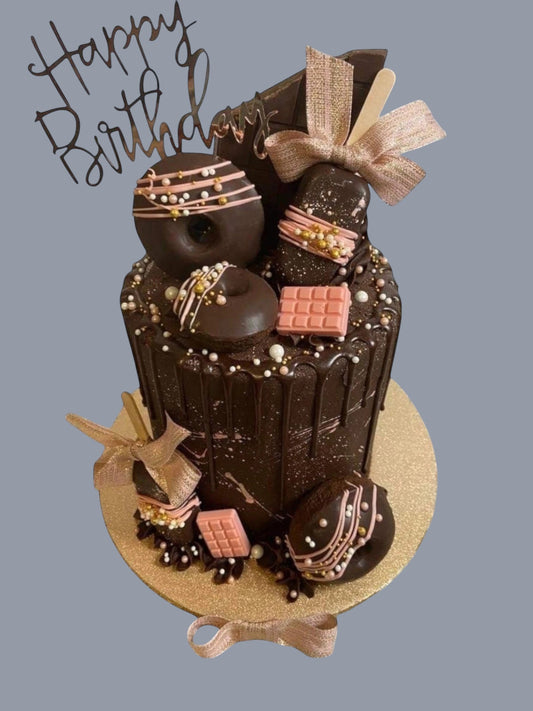 Sarah's Cakes luxury loaded chocolate birthday cake with donuts, chocolate bars, and pink accents.
