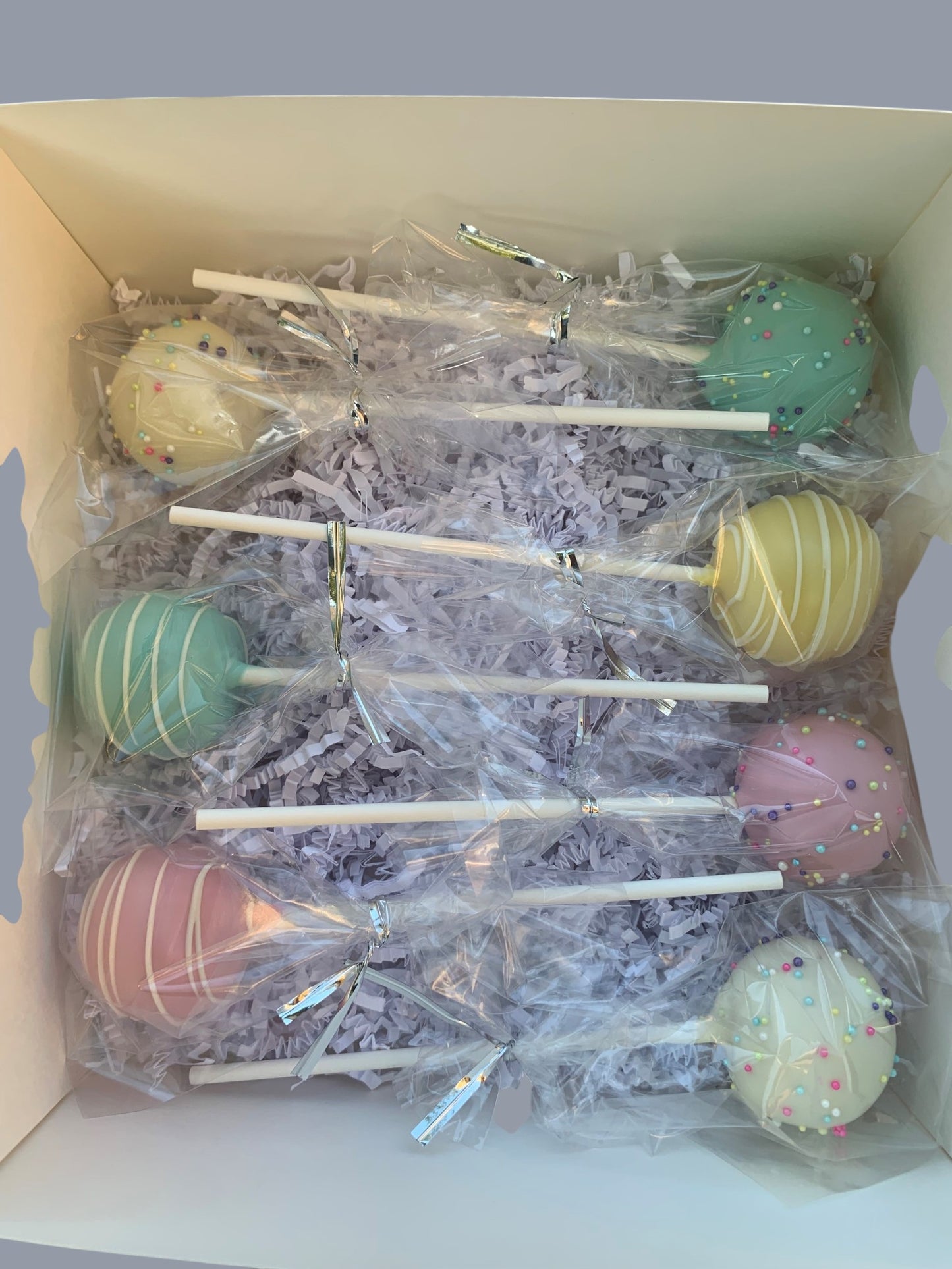 Sarah's Cakes pastel cake pops in mint green, pale yellow, pink, and white with sprinkles and stripes.