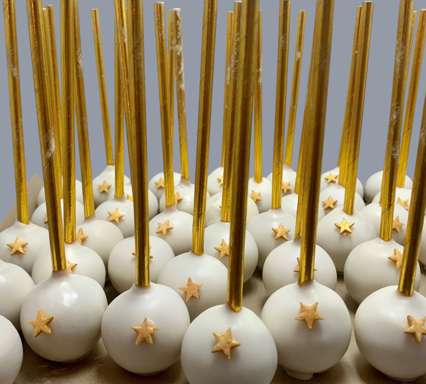 Sarah's Cakes white cake pops with gold star decorations and gold sticks, sold by the dozen.